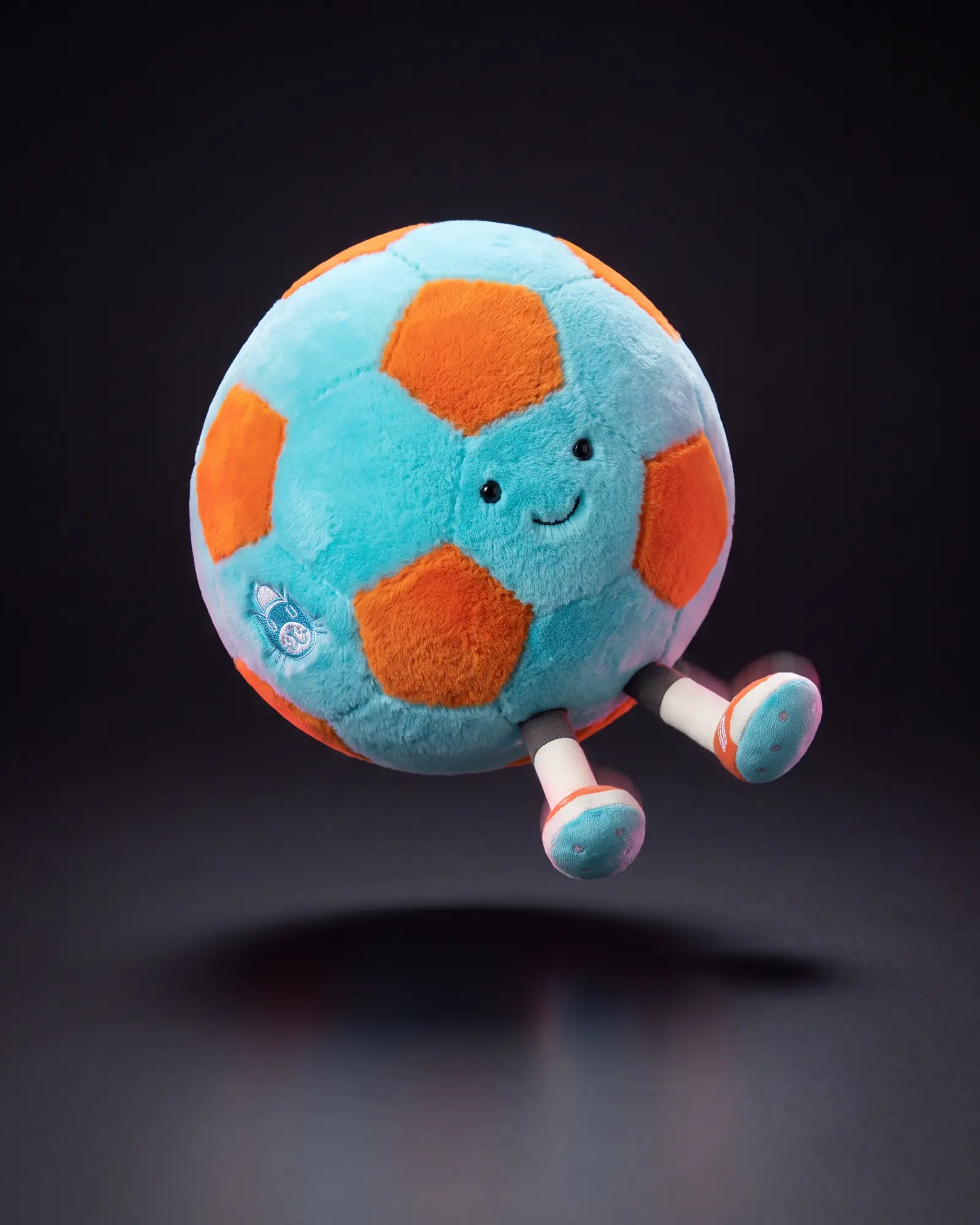 Amuseables Jellycat Football, 어두운 스튜디오 배경.
